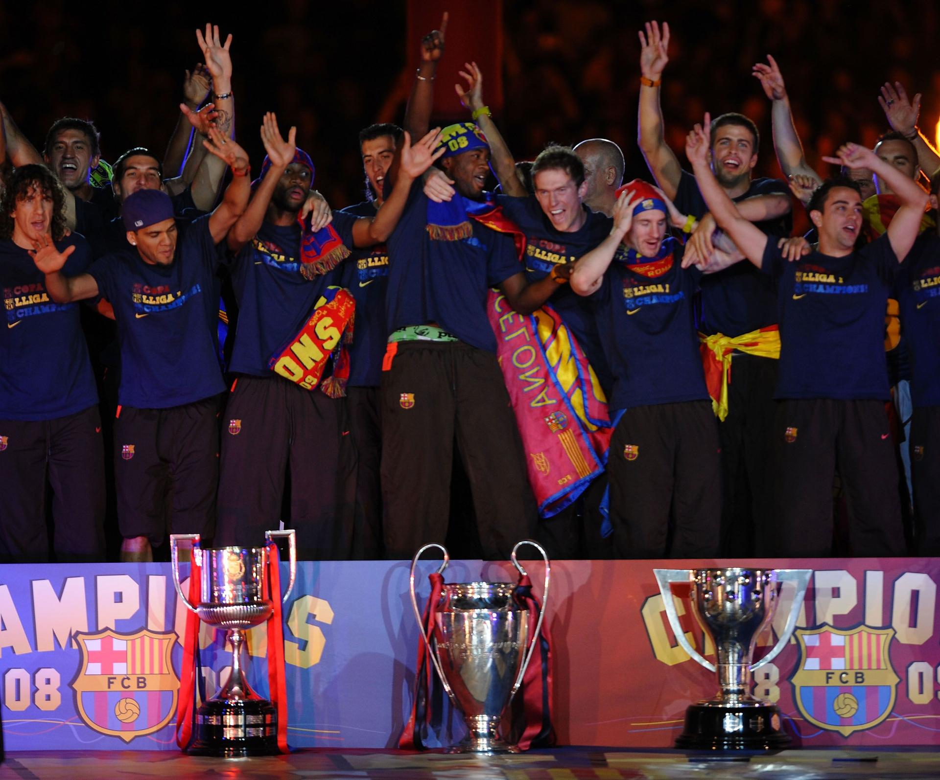 Barcelona players celebrate beside their three thophys